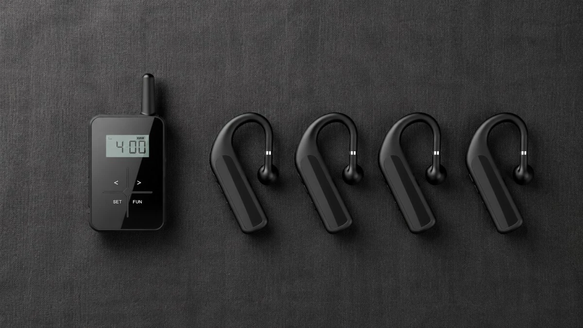 Flat lay of a complete wireless tour guide system including transmitter multiple receivers earphones and charging dock arranged on a dark linen background Flat lay of a complete wireless tour guide system including transmitter multiple receivers earphones and charging dock arranged on a dark linen background